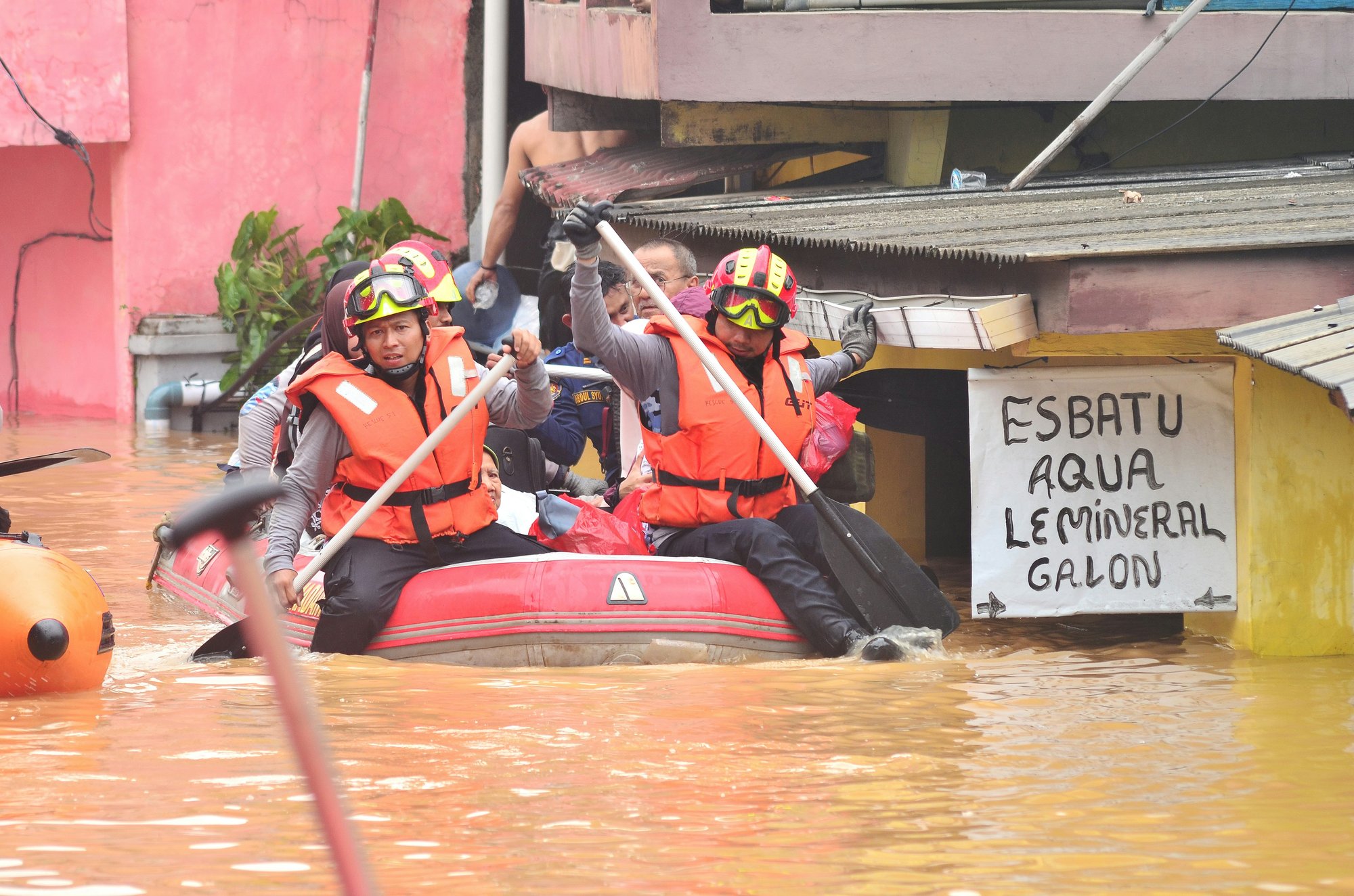 Photo of rescue people in a boat with a sign in Spanish that reads "Esbatu aqua le mineral galon."